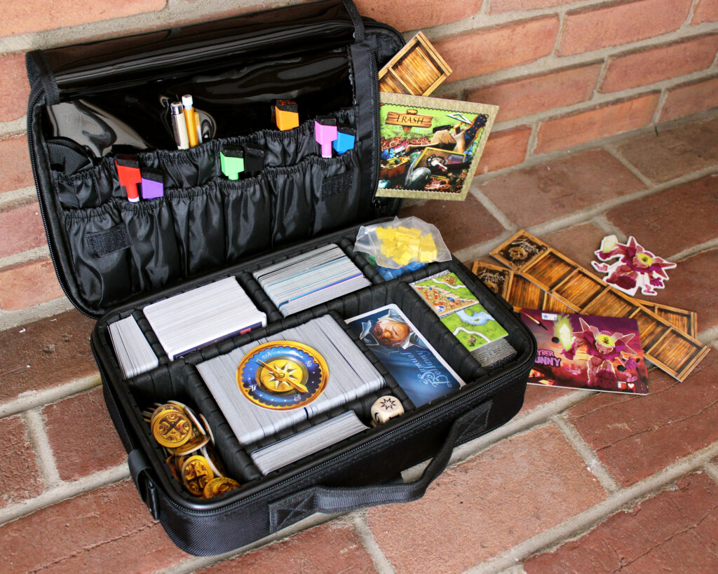 Board game travel case filled with a variety of games: Jamaica, Carcassonne, Moonrakers, King of Tokyo, Dominion, Pandemic and more